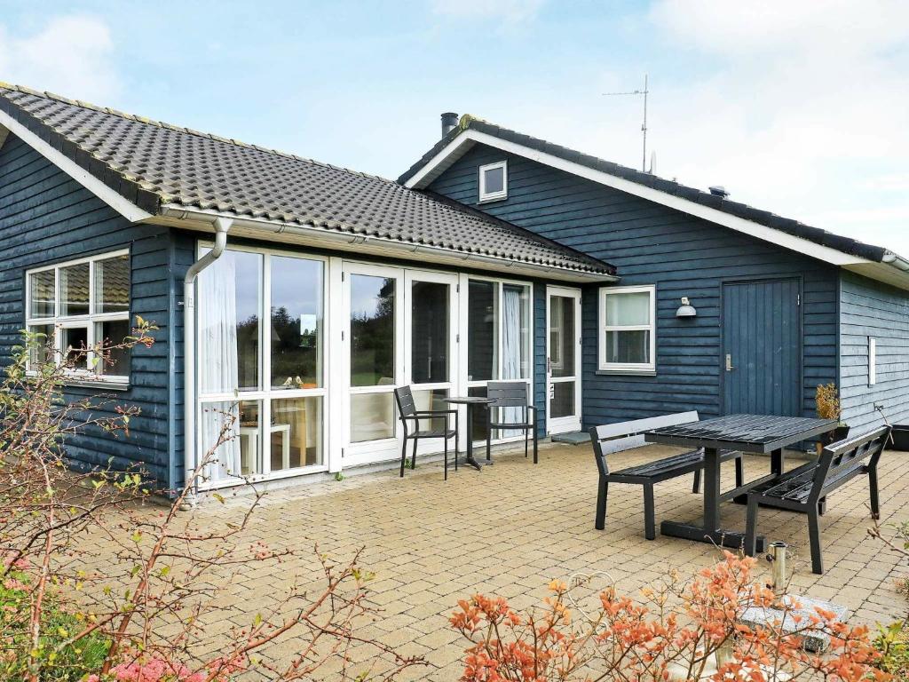 Casa azul con patio con mesa y sillas en Holiday home Sæby II, en Saeby