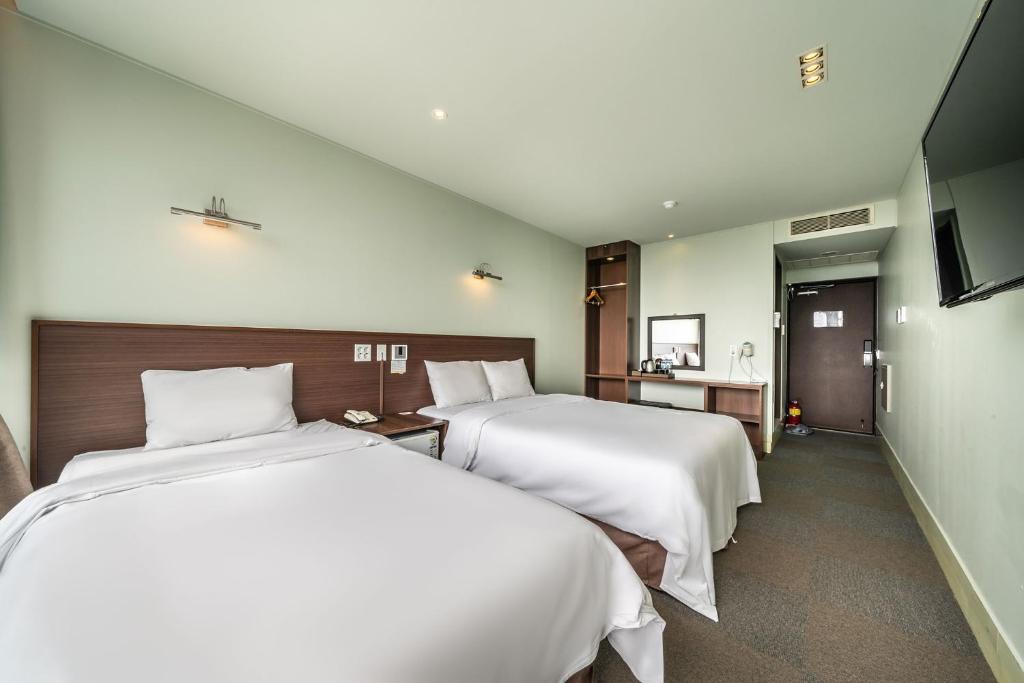 Postel nebo postele na pokoji v ubytování Sunrise Hotel Jungmun Branch