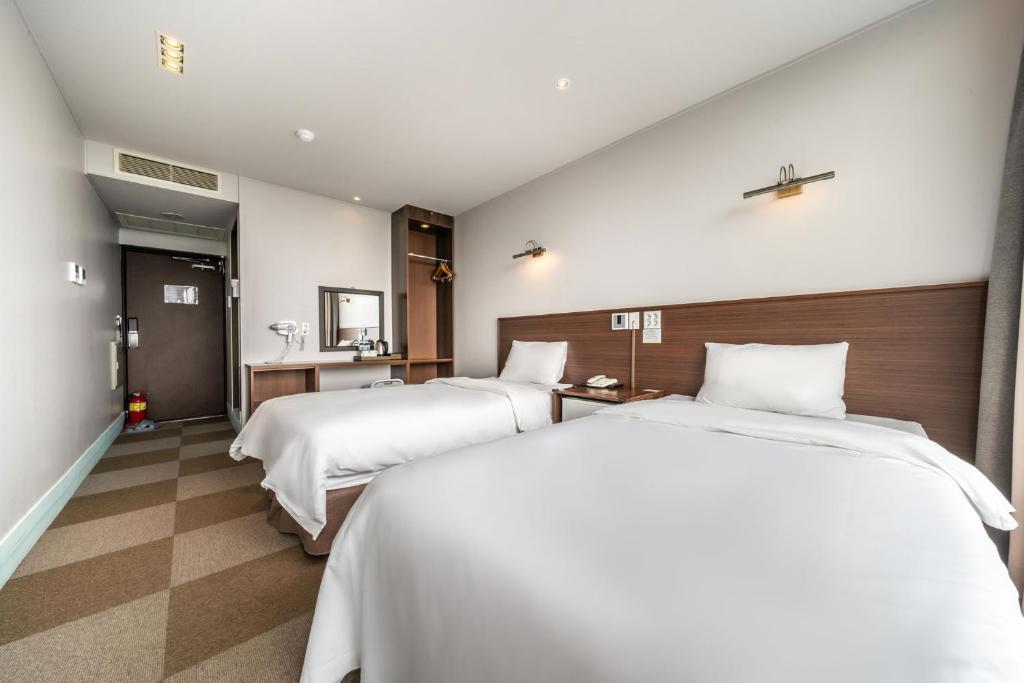 Postel nebo postele na pokoji v ubytování Sunrise Hotel Jungmun Branch