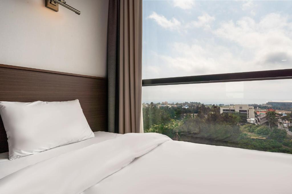 Postel nebo postele na pokoji v ubytování Sunrise Hotel Jungmun Branch