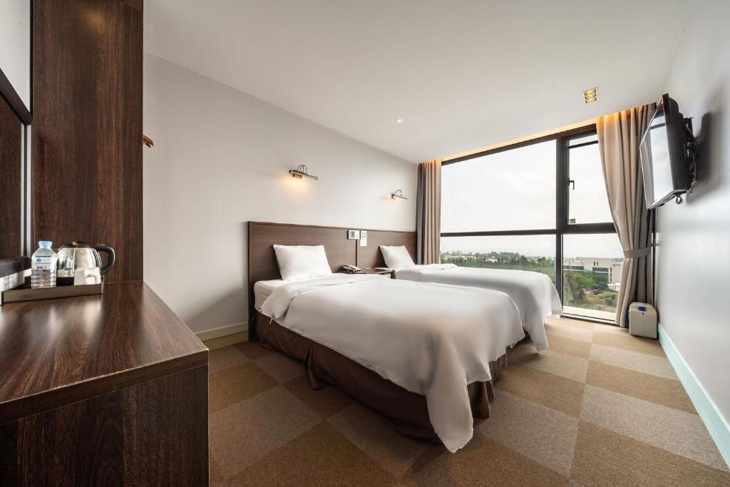 Postel nebo postele na pokoji v ubytování Sunrise Hotel Jungmun Branch