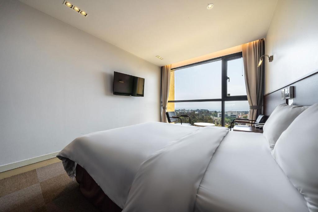 Postel nebo postele na pokoji v ubytování Sunrise Hotel Jungmun Branch