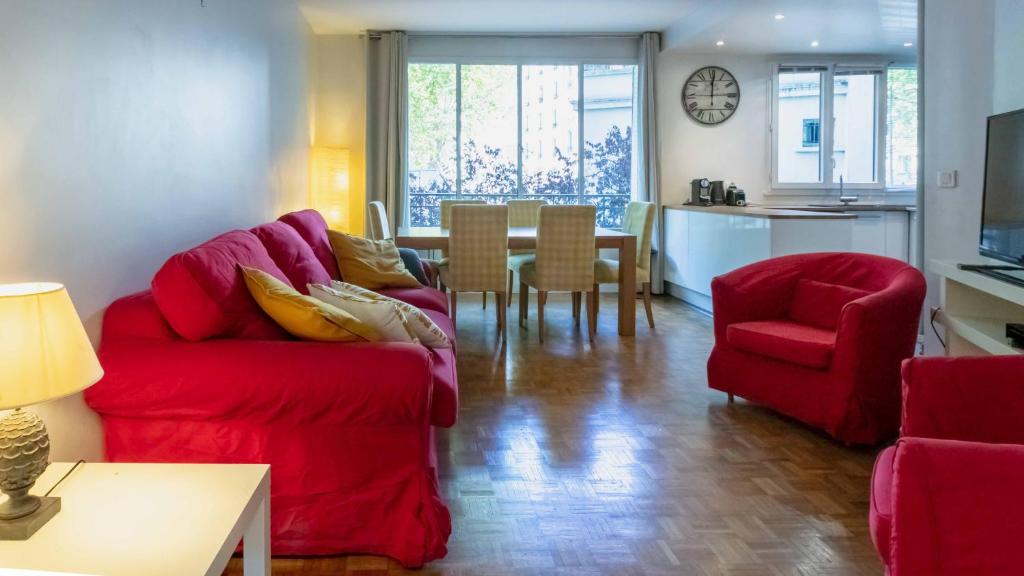 a living room with a red couch and a table at Paris City - Spacious 3 rooms flat for families - 3 minutes from metro station in Paris