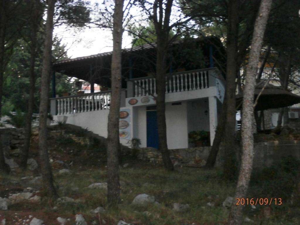 a small white house with a porch and trees at Apartments Meni in Drage