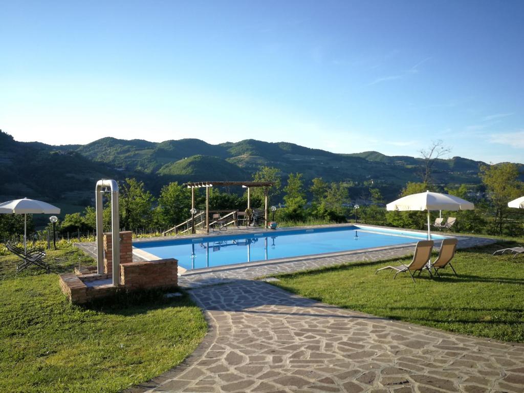 a swimming pool with chairs and umbrellas at Agriturismo - Tenuta MonteOliveto - Cottage Romantic in Vesime