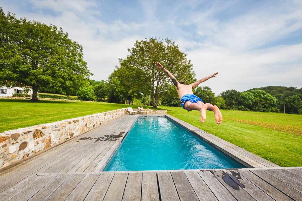 a man jumping into a swimming pool at RETREAT KEYWEEK House with Character Pool Fireplace and Garden in Arcangues