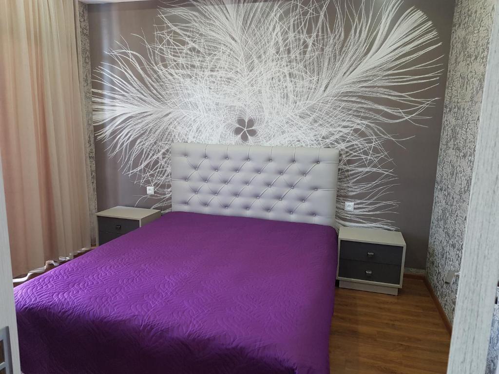 a bedroom with a purple bed and a wall at Your home in Kutaisi