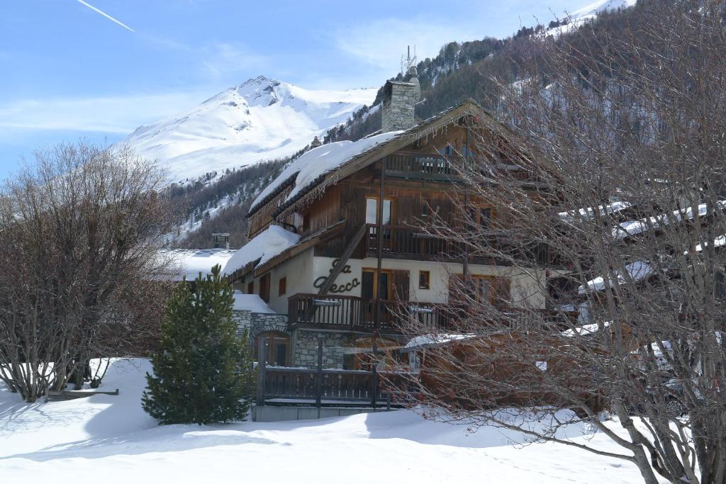 una cabaña de madera en la nieve con una montaña en Chalet La Becca, en Le Fornet