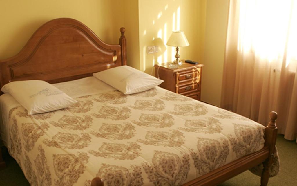Hotel Xallas في Santa Comba: غرفة نوم بسرير وطاولة مع مصباح