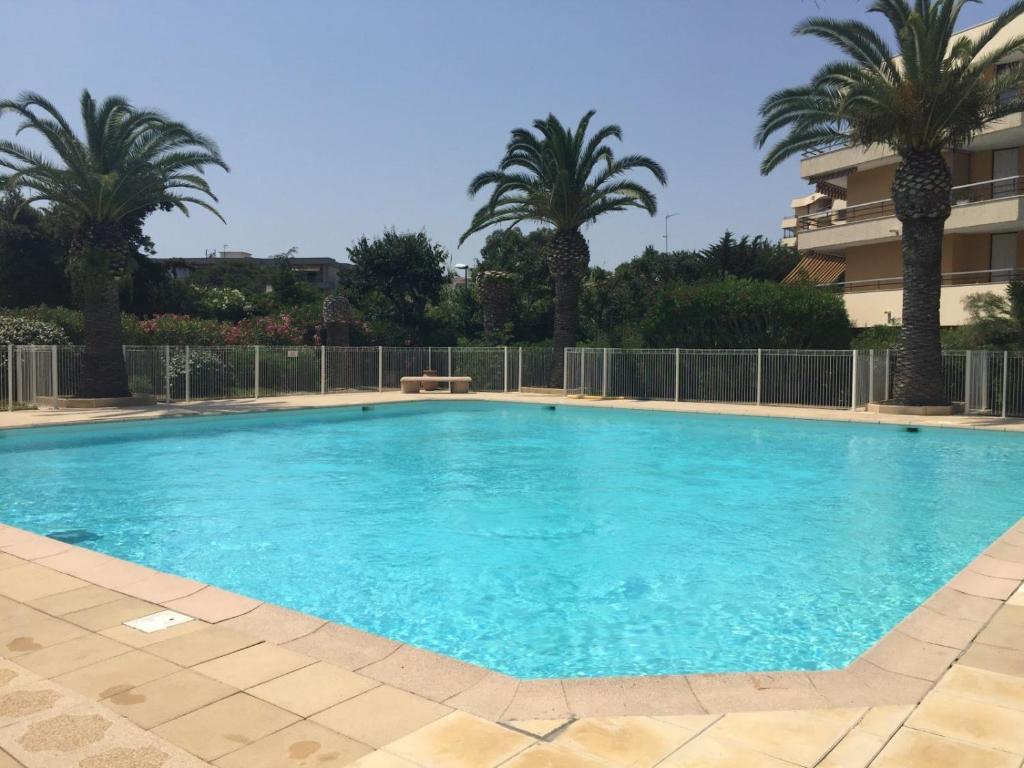 einem großen Pool mit Palmen und einem Gebäude in der Unterkunft Fréjus plage T2, piscine, parking, plages à 200m in Fréjus
