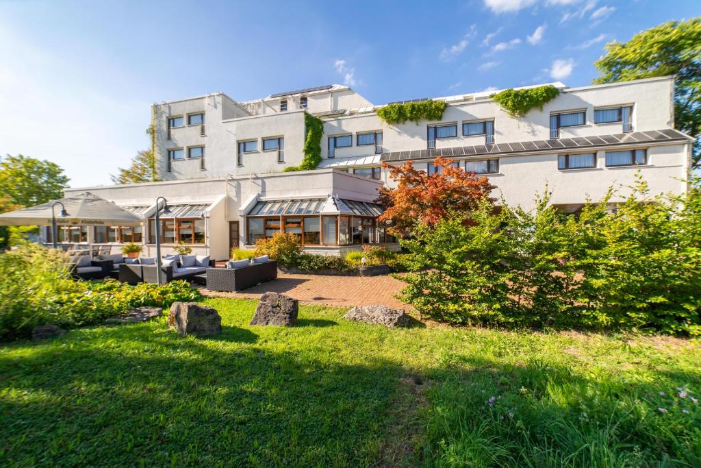 - un grand bâtiment blanc avec un jardin en face dans l'établissement Stadt-gut-Hotel Filderhotel, à Ostfildern