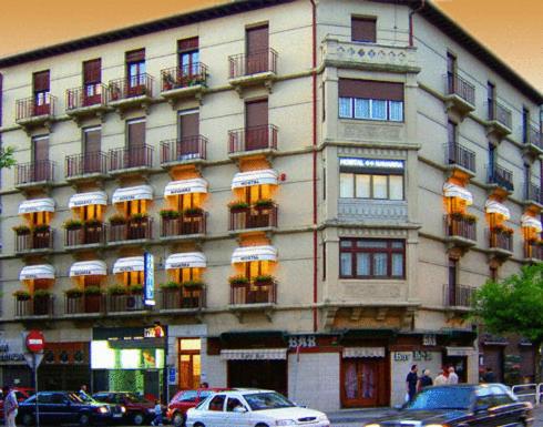 un edificio alto con coches estacionados frente a él en Hostal Navarra, en Pamplona