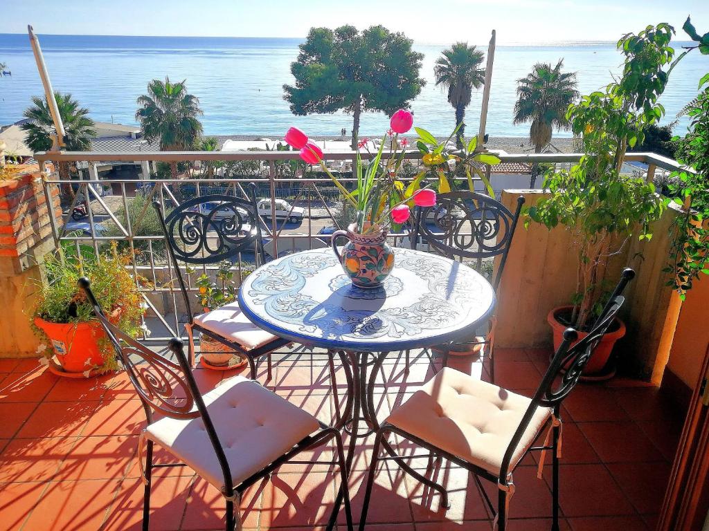 een tafel en stoelen op een balkon met uitzicht op de oceaan bij Taormina by the sea in Mazzeo