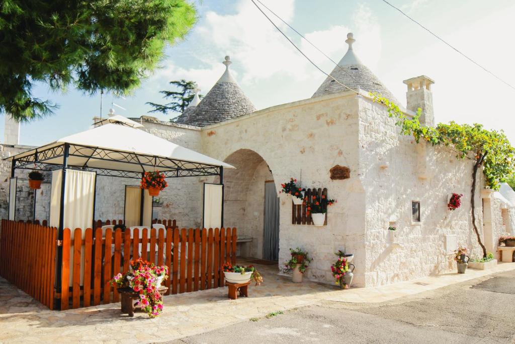 ein weißes Gebäude mit einem Tor und einem Zaun in der Unterkunft Trulli Borgo Lamie in Locorotondo