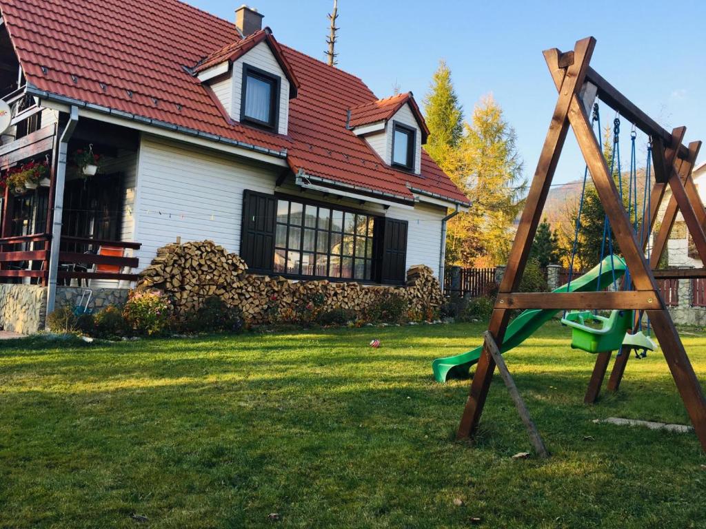 um quintal com um parque infantil em frente a uma casa em Vila Lucia em Colibiţa