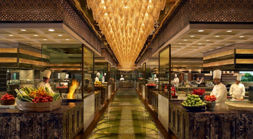 a kitchen with chefs preparing food in a restaurant at The Leela Ambience Gurugram Hotel & Residences - The Luxury Urban Sanctuary in Gurgaon