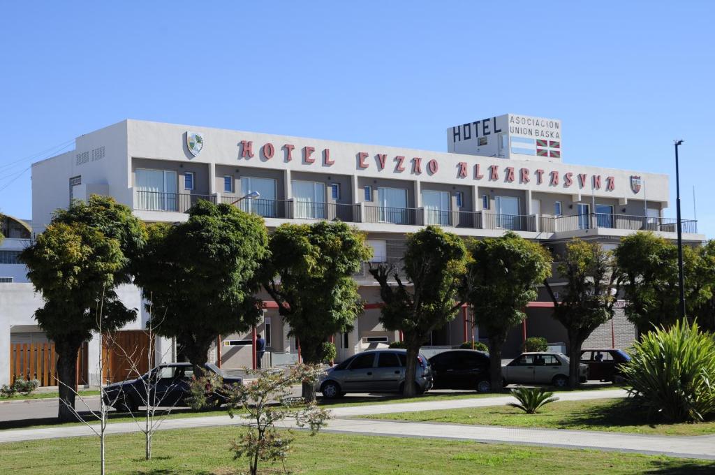 a hotel with cars parked in front of a building at Hotel Euzko Alkartasuna in Macachín