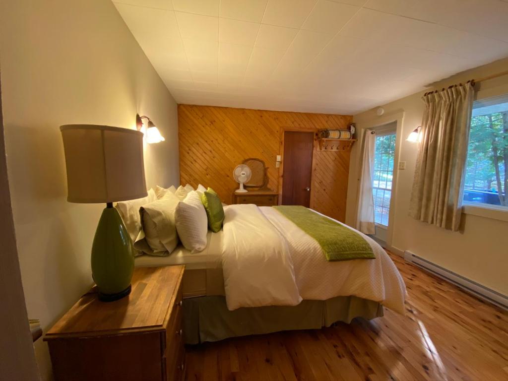 a bedroom with a bed and a lamp on a table at Chalets et Studios Le Vent Du Nord in Lac-Superieur