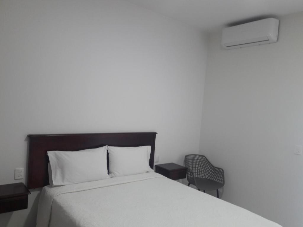 1 dormitorio con 1 cama blanca y 1 silla en HOTEL FINA INN, en La Barca