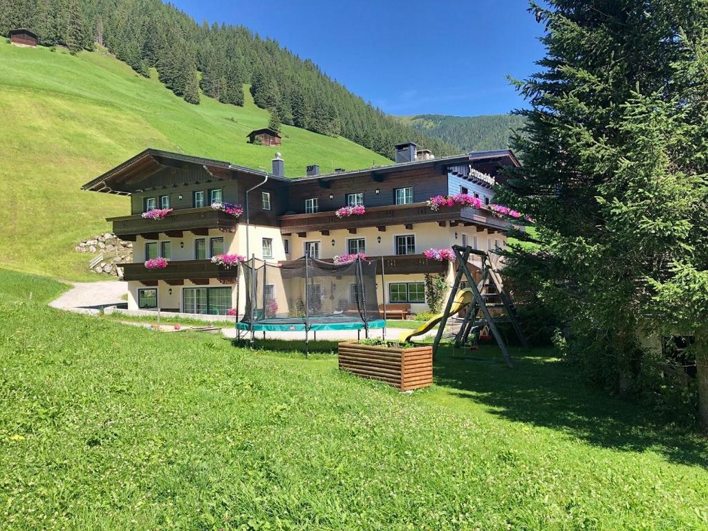 una casa grande en una colina con parque infantil en Jenneweinhof, en Tux