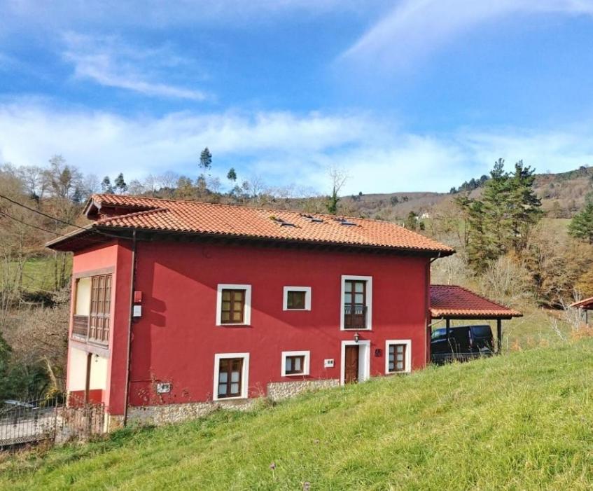 una casa rossa sul fianco di una collina di La Riega II a Argandenes