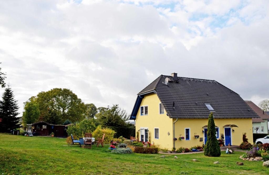 a yellow house with a black roof on a green field at Ferienappartements in Gager auf Ru in Gager