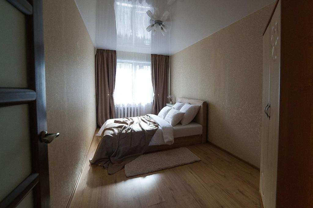 a bedroom with a bed with white pillows and a window at PaulMarie Apartments on Molodeznaya in Soligorsk