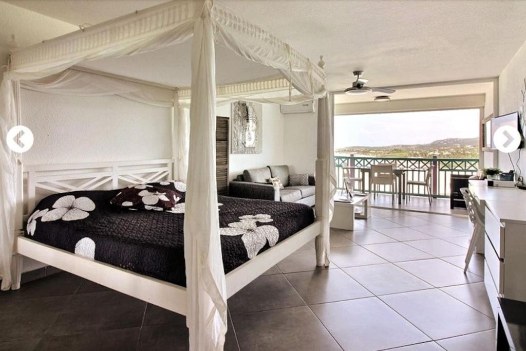 1 dormitorio con cama con dosel y balcón en Un petit coin de paradis - Ocean view Orient Bay - St Barthélémy, en Cul de Sac