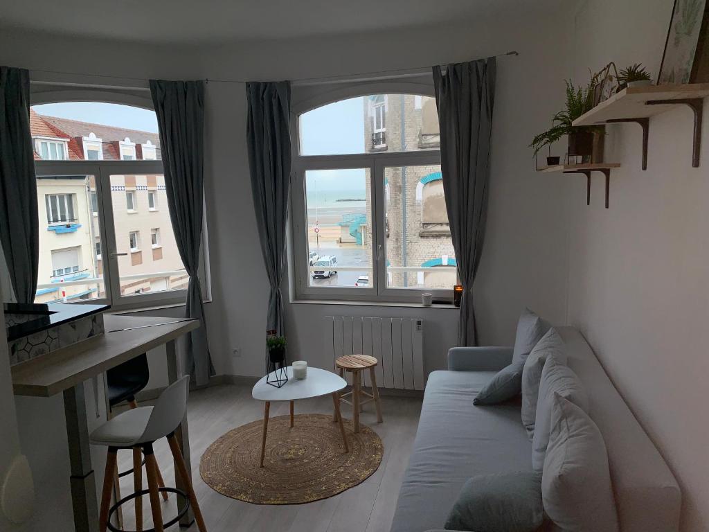 een woonkamer met een bank, een tafel en een raam bij Appartement vue mer poste bleu in Malo-les-Bains