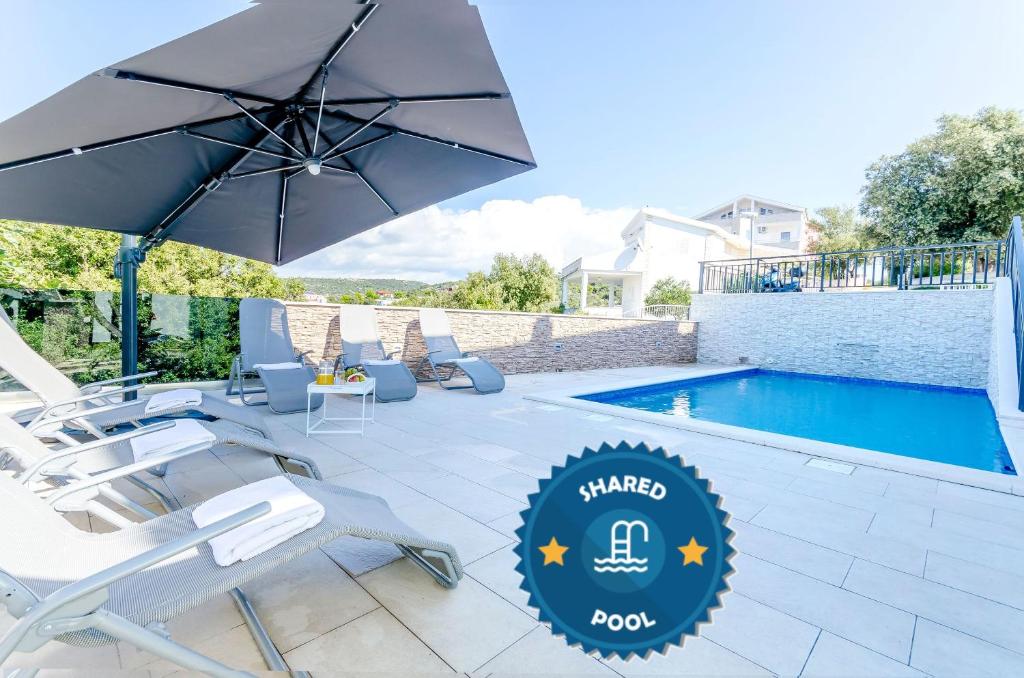 a patio with chairs and an umbrella next to a swimming pool at Apartments Katic in Ražanj