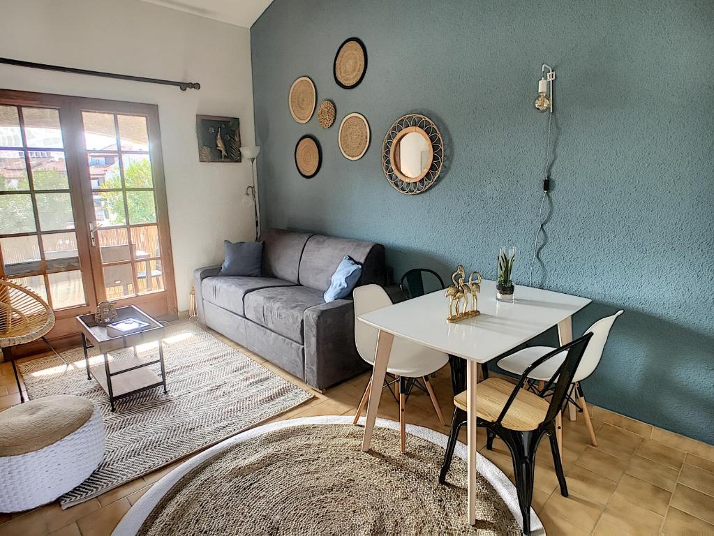 ein Wohnzimmer mit einem Tisch und einem Sofa in der Unterkunft Superbe Duplex aux Saintes terrasse plein sud 3*** in Saintes-Maries-de-la-Mer