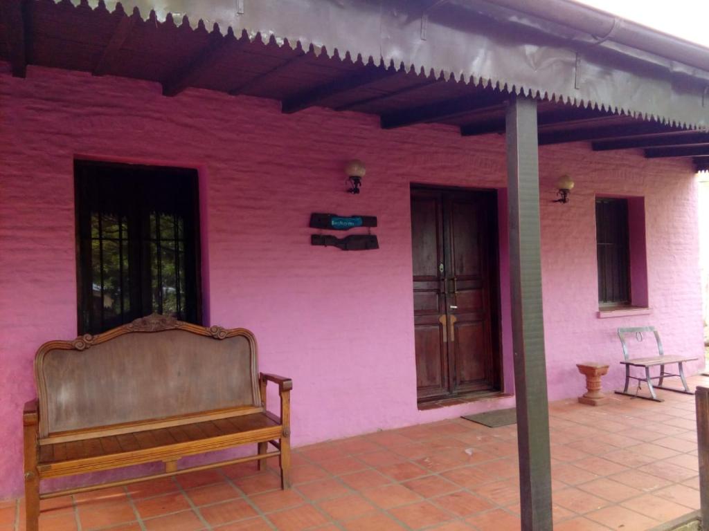 a bench sitting in front of a pink building at Hostal El Puesto in Salto