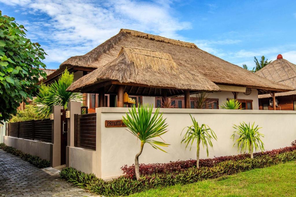 une maison avec un toit de chaume et des palmiers dans l'établissement Villa Agung, à Nusa Lembongan