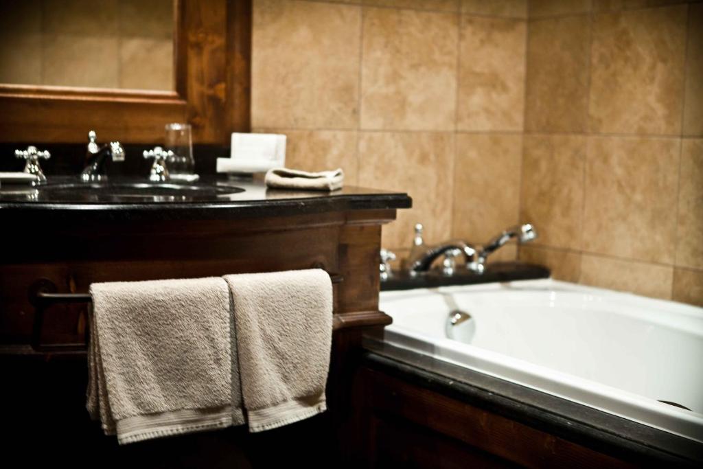 a bathroom with a tub and a sink with towels at Hôtel Les Barmes De l'Ours in Val-d'Isère