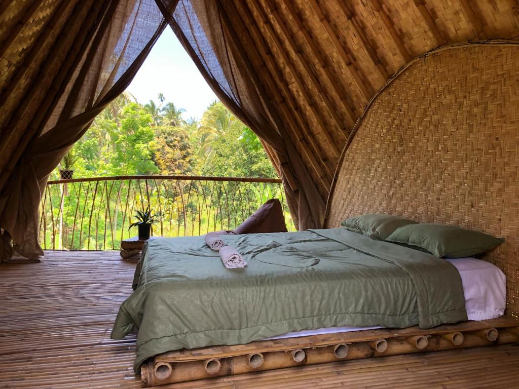 a bed in a tent on a wooden deck at Bamboo & B in Licin