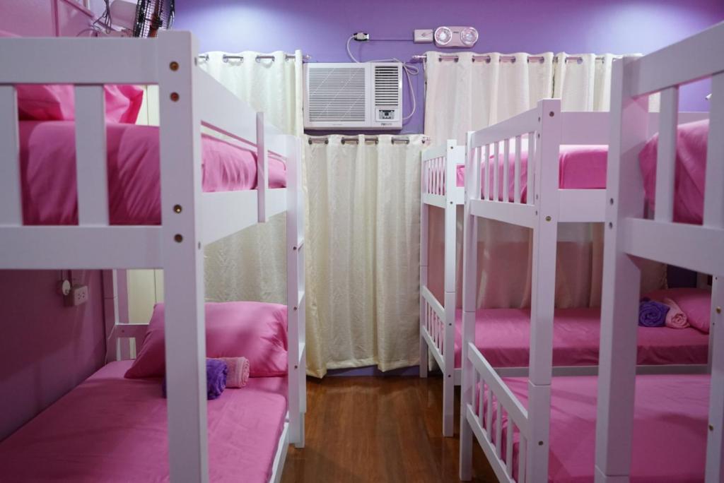 een slaapkamer met 2 stapelbedden met roze lakens bij Peach Haven in Cebu City