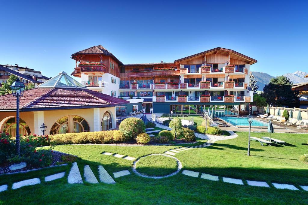 ein großes Gebäude mit einem Garten vor einem Resort in der Unterkunft Mirabell Dolomites Hotel Luxury Ayurveda & Spa in Olang