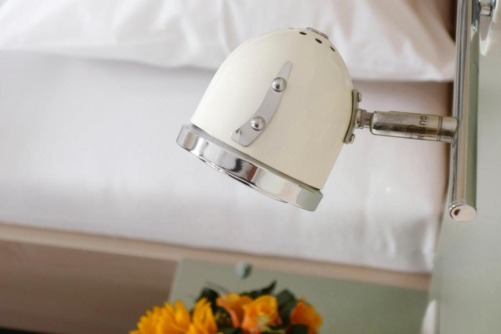 a mirror on a wall next to a vase of flowers at Best Deal Airporthotel Weeze in Weeze