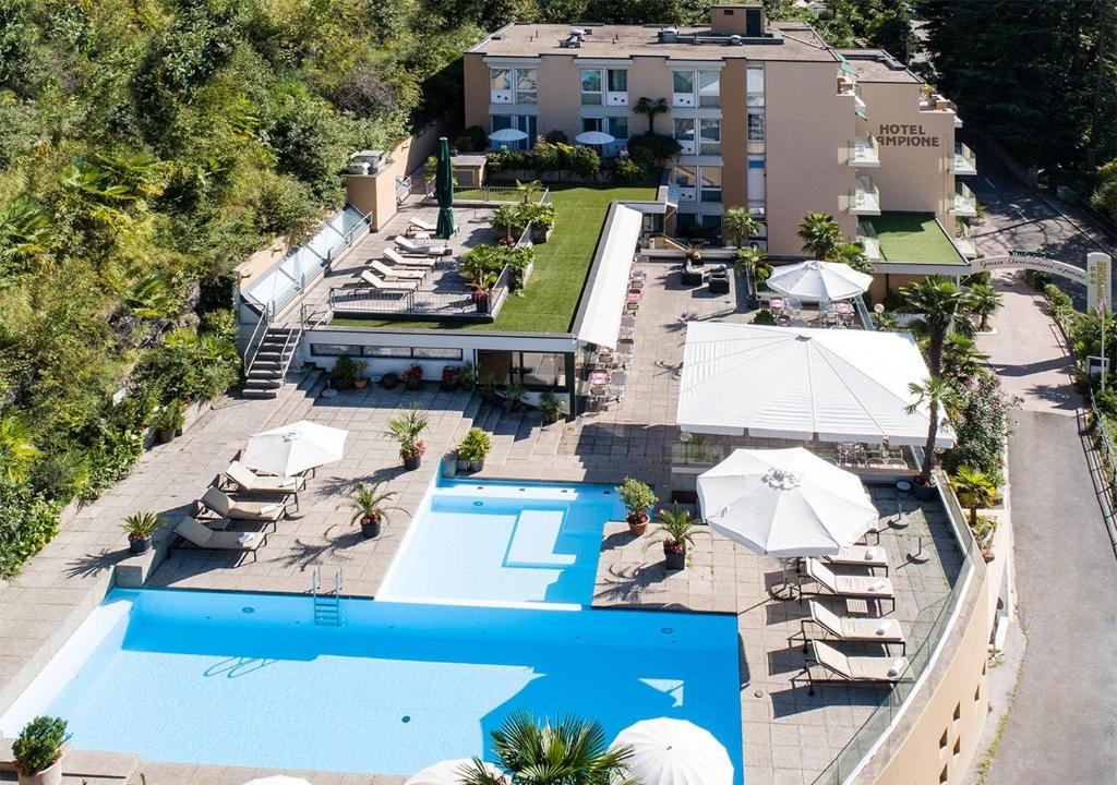 eine Luftansicht eines Resorts mit Pool und Sonnenschirmen in der Unterkunft Hotel Campione in Bissone