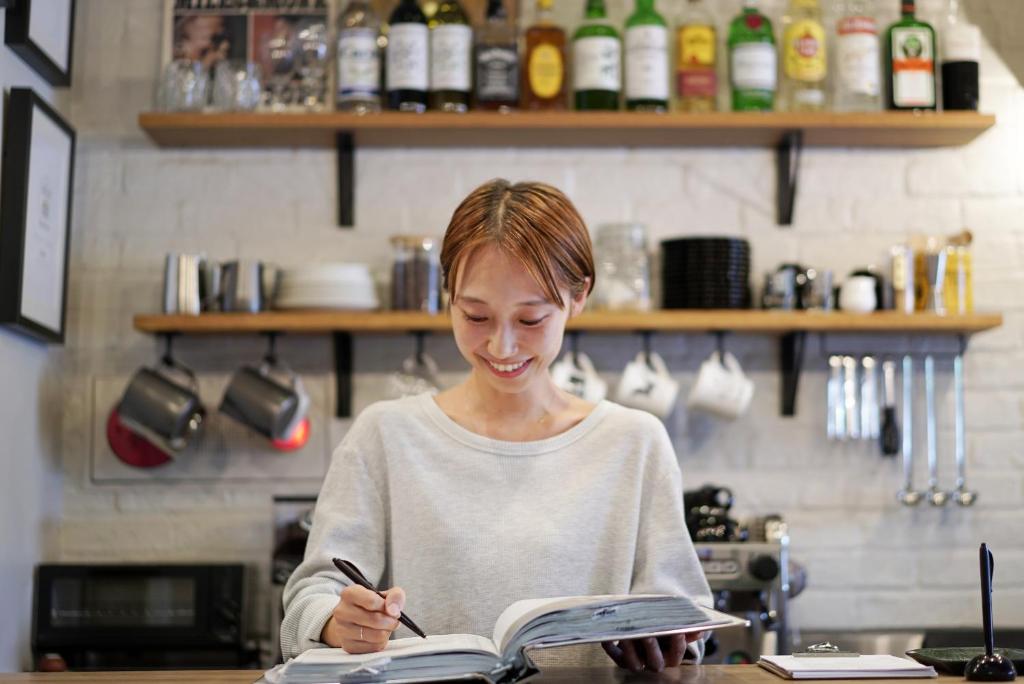 a woman sitting at a table writing in a book at Hotel Pacific Kanazawa in Kanazawa