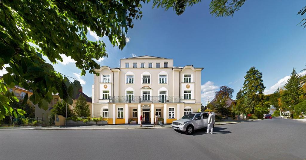 una macchina bianca parcheggiata di fronte a un edificio di Wellness Hotel La Passionaria a Mariánské Lázně