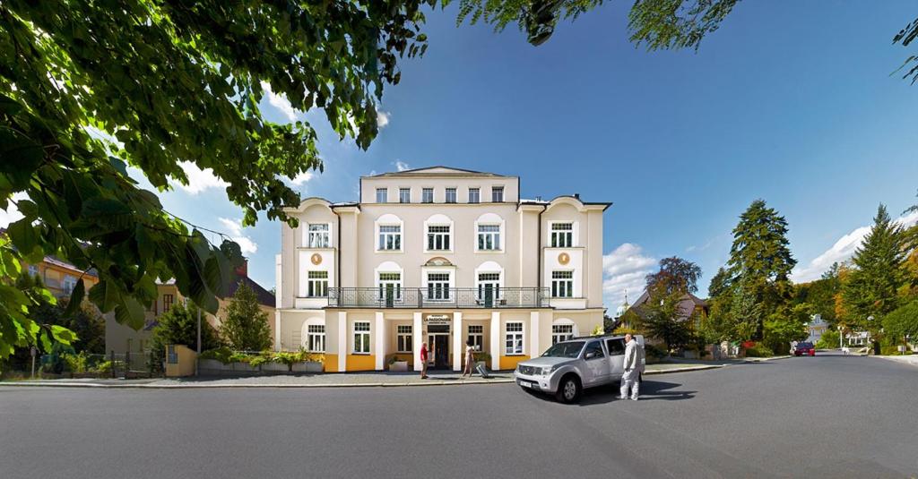 una macchina bianca parcheggiata di fronte a un edificio di Hotel La Passionaria a Mariánské Lázně