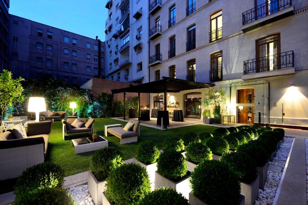 a garden with couches and bushes in front of a building at Hotel Único Madrid, Small Luxury Hotels in Madrid