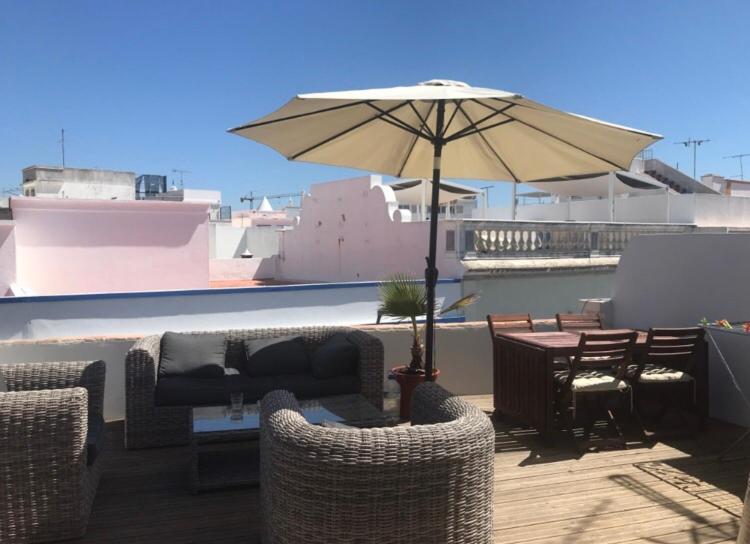 un patio con una mesa y una sombrilla en el techo en Olhao Citycentre Apartment, en Olhão