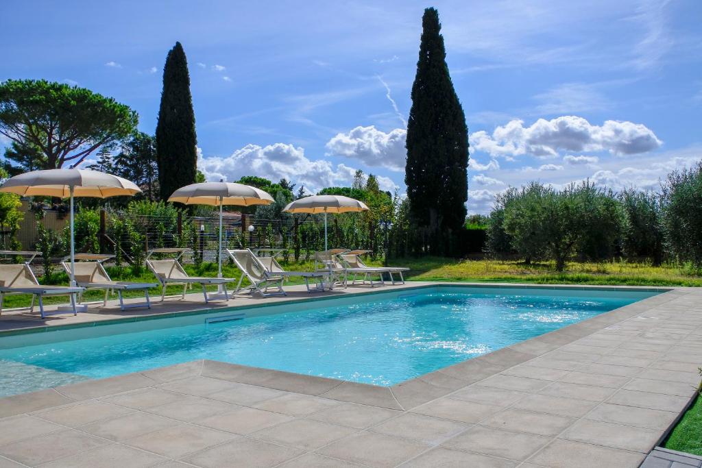 a swimming pool with chairs and umbrellas at Poggio Picchio in Bibbona