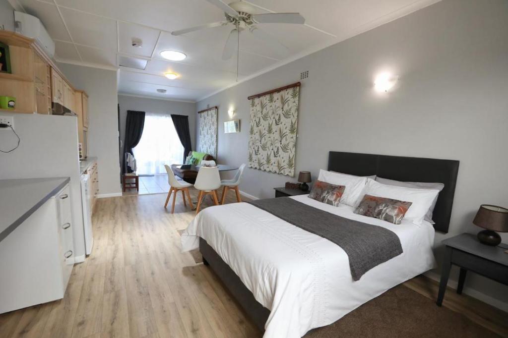 um quarto com uma grande cama branca e uma cozinha em Caesar's Self-catering Open Plan Suite em Somerset West