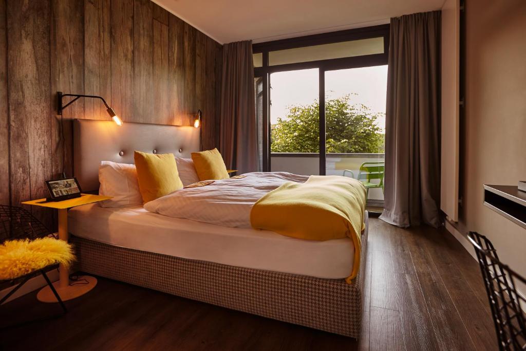 - une chambre avec un grand lit et une grande fenêtre dans l'établissement Gästehaus des Elsa Brändström Haus, à Hambourg