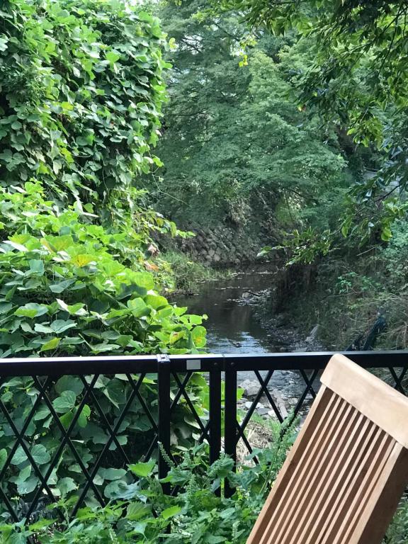 un banco sentado en una barandilla junto a un río en Children's cafe B&B Kimie, en Kamakura