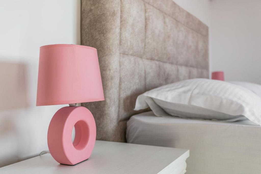 una lámpara rosa sentada en una mesa junto a una cama en Apartments Aleksandar, en Petrovac na Moru