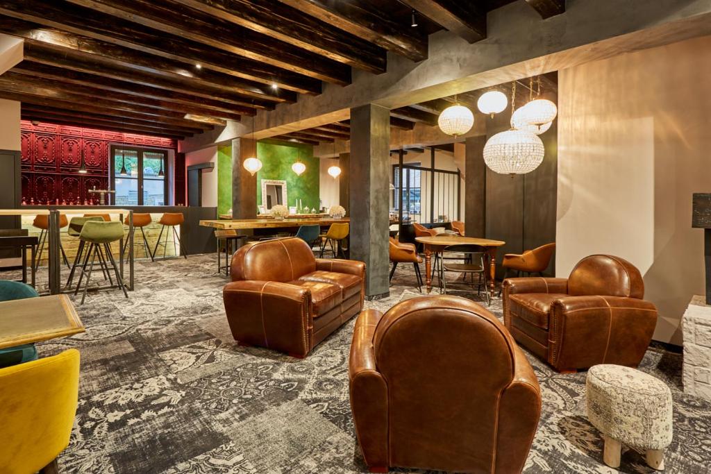 un hall avec des chaises et des tables en cuir ainsi qu'un bar dans l'établissement Hôtel-SPA Le Moulin De La Wantzenau - Strasbourg Nord, à La Wantzenau